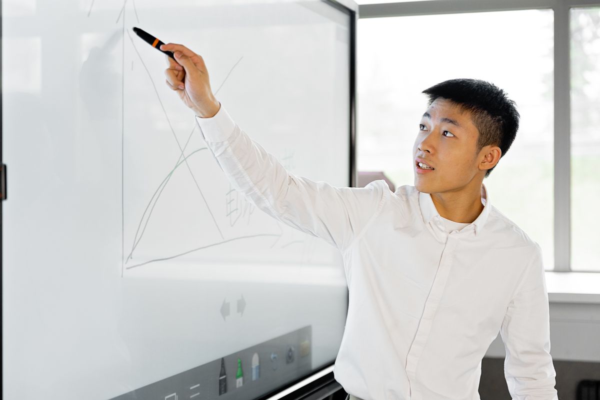 Người trình bày đang giải thích biểu đồ trên bảng cạnh cửa sổ sáng
